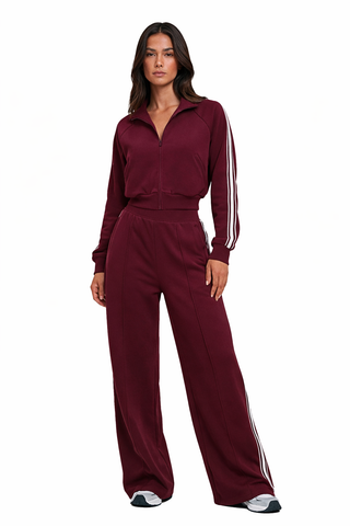 Woman wearing a burgundy tracksuit with white stripes on a white background